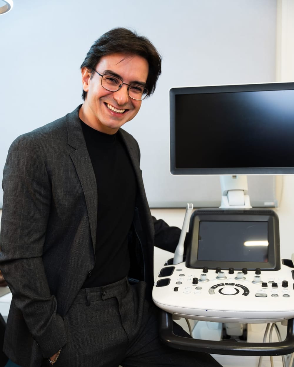 Dr. Luiz Henrique Schiavon ao lado do aparelho de ultrassonografia usado nos procedimentos guiados por imagem